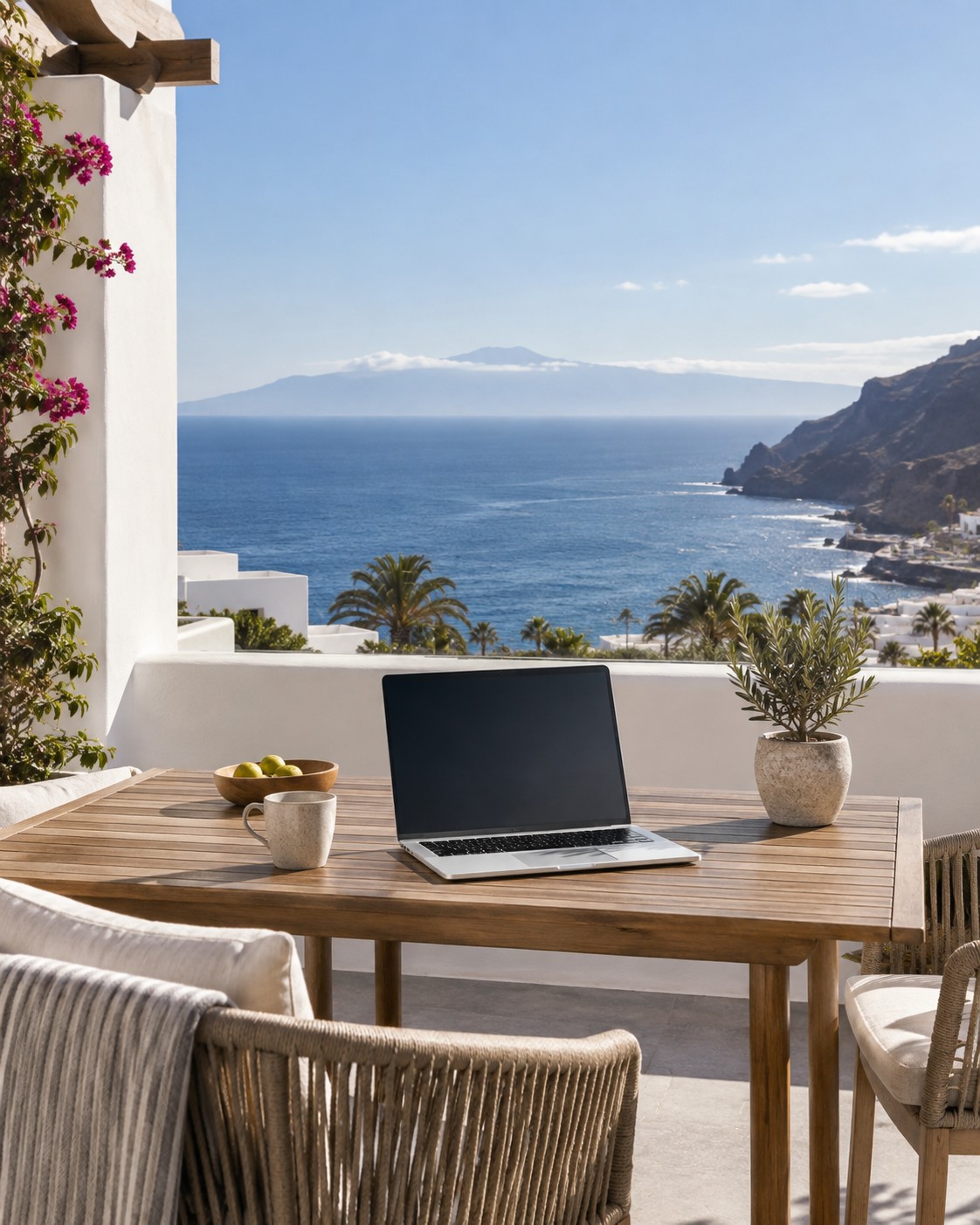 Illustrative image: bright holiday apartment terrace with a laptop and an ocean view